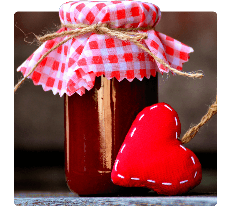 A jar of jam with a red heart on top.