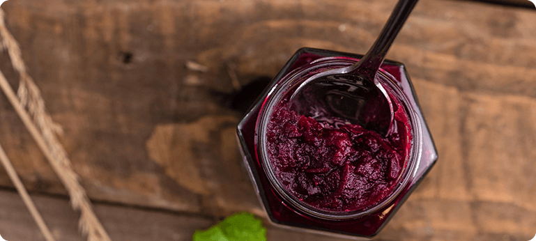 A jar of cranberry sauce with a spoon in it.