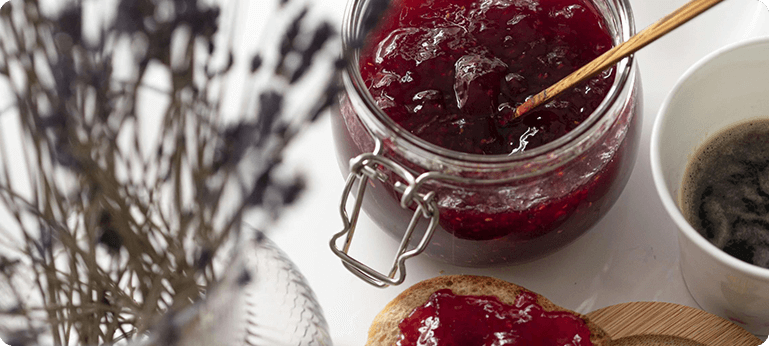 A jar of jam on top of a table.